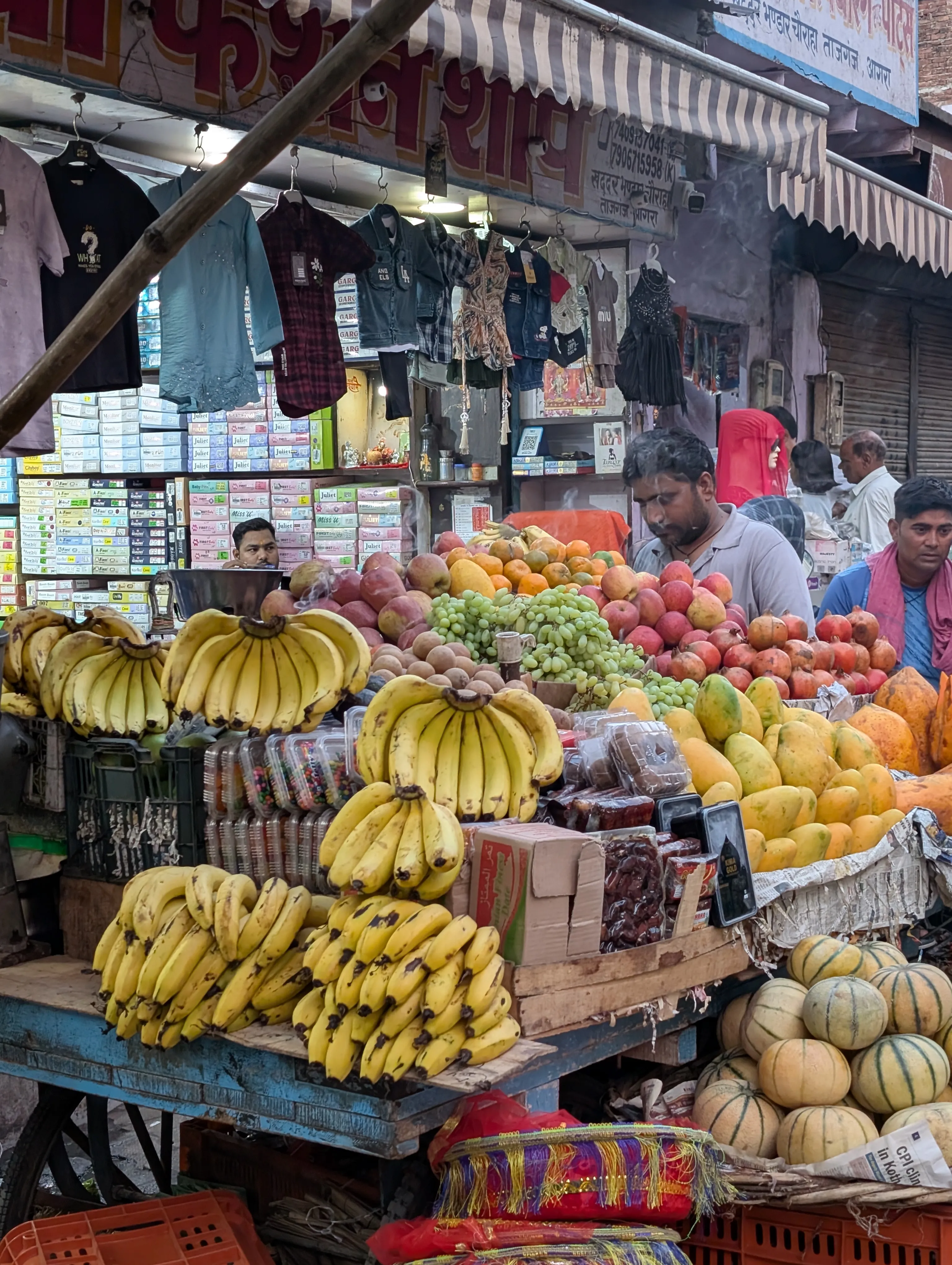 A fruit stall overflowing with bananas, mangoes, and grapes.