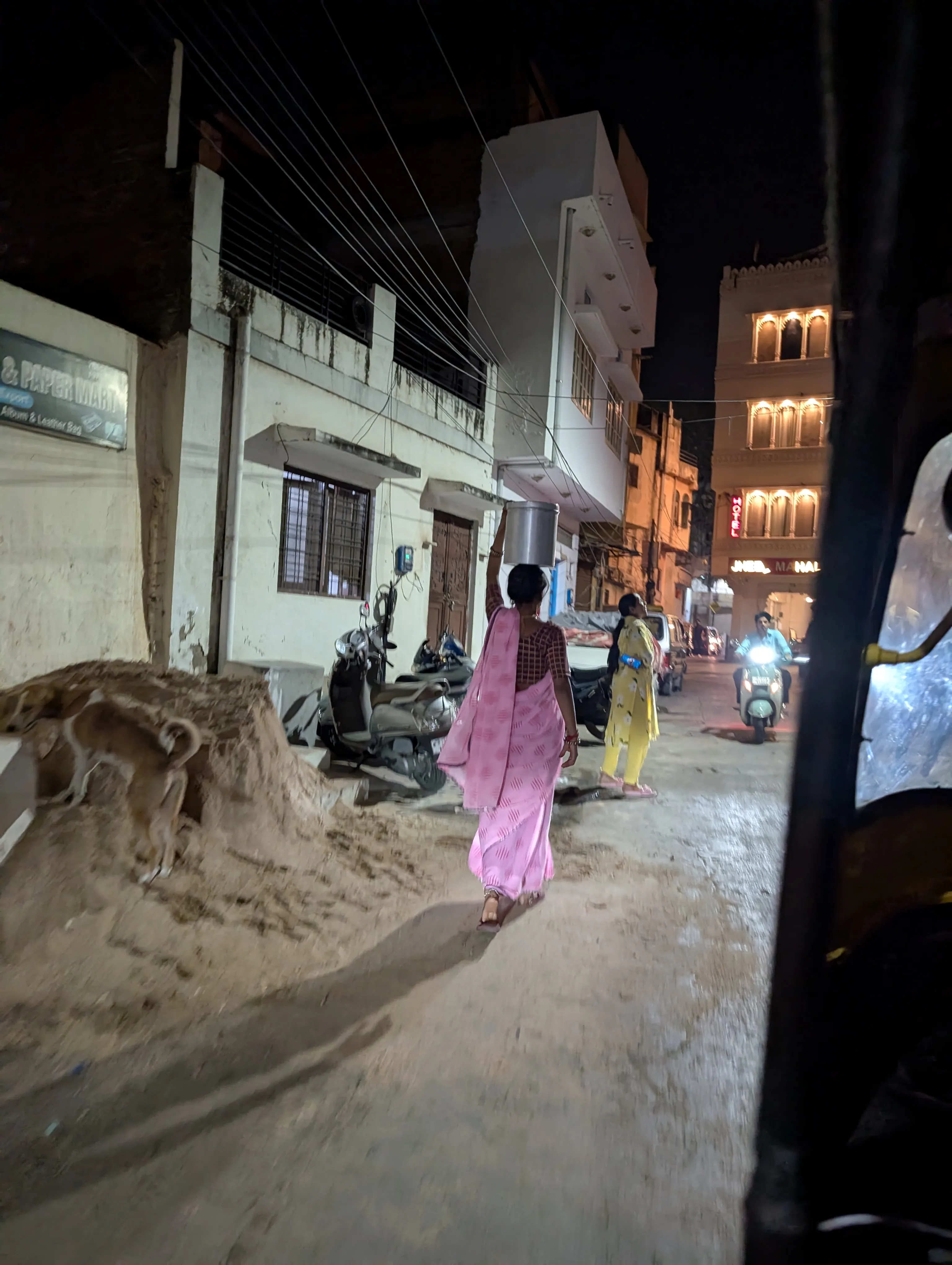 A woman in a pink sari carries a pot through the streets, shot from our tuk-tuk.